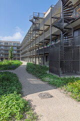 Modern modular housing in Utrecht, Netherlands, featuring multi-story temporary apartments with spiral staircases and shared green spaces, addressing urban housing shortages.
