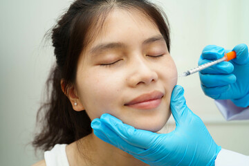 Asian woman receiving lip contouring procedure augmentation performed on face.