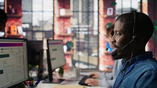 Diverse customer center workers assisting clients with installing software. Multiethnic team of call center agents using remote access tools to connect to customer devices, fixing errors, camera B - Powered by Adobe