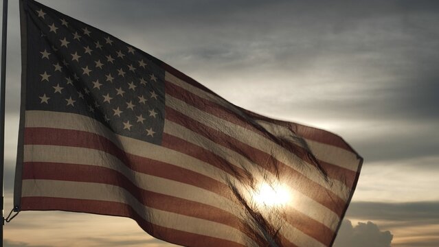 Close up USA American flag waving in the sky against sunset, sunrise outside background. Concept Fourth of July, 4th of July, Independence Day, Veteran Day, Holiday, Celebration. Freedom, Celebration