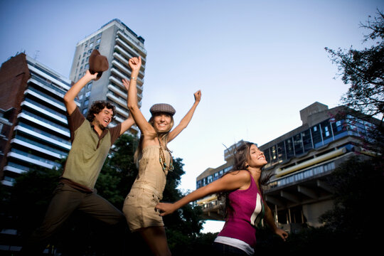 Three Friends Jumping Joyfully Outdoors in Urban Setting