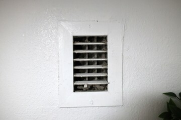 dust and dirt buildup visible on the wall-mounted air conditioner's exhaust vent showing lack of maintenance and poor air quality in close up view