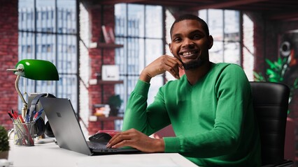 African american remote worker solving his daily freelancing tasks on laptop, working in relaxation...