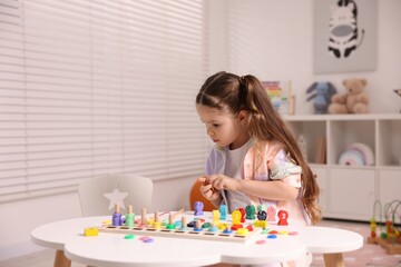 Motor skills development. Little girl playing with math game Fishing for Numbers at white table indoors