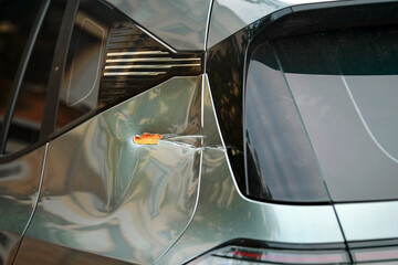 Scratched and dented rear car body with visible rust patches, paint damage surrounding trunk lid...