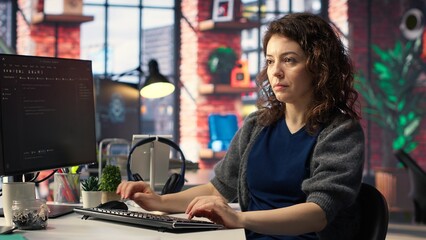 IT female technician uses coding language on computer at the agency, creating software to work on...