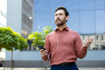 A man in an office setting speaks on the phone with an earpiece. Modern urban lifestyle