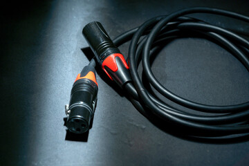 Closeup view of an audio jack cable on a black background. XLR audio cable