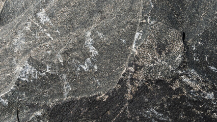 Dark grey stone texture showing white veins and cracks forming natural pattern