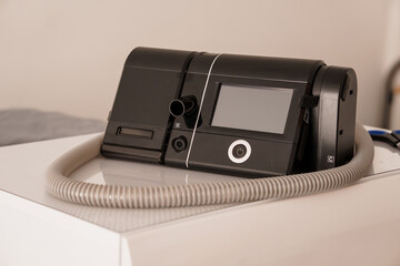 Modern Black CPAP Machine with Humidifier on White Table, Healthcare Technology Device, Sleep Apnea...