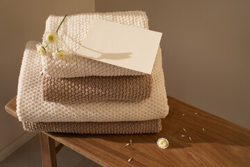 Stack of towels in neutral colors and paper blank in modern aesthetic interior. Fabric bathroom accessories for hygiene, spa and skin care.