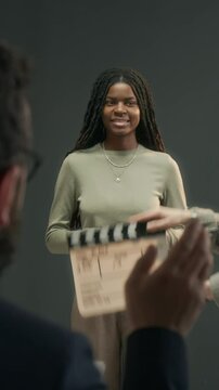 Vertical shot of African American actress listening to unrecognizable filming direcor speaking to her on set