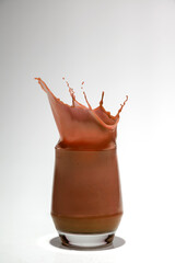Chocolate in a glass with a splash on a white background