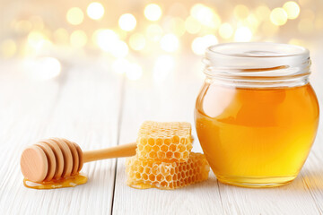 Sweet honey in jar, honeycombs and wooden spoon on wooden table with copy space on festive magical background
