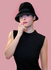 Une femme l'air pensive en haut sans manches noir et chapeau noir pose contre un fond rose
