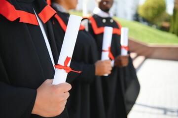 Group of multiracial graduate students with diplomas on university background