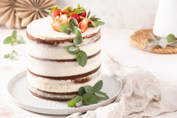 Rustic naked cake with strawberries and eucalyptus on a white background