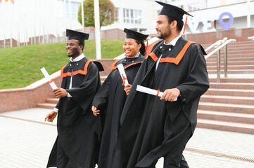 education, graduation and people concept - group of happy international students in mortar boards...
