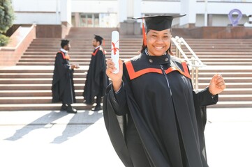 pretty african female college graduate at graduation with classmates