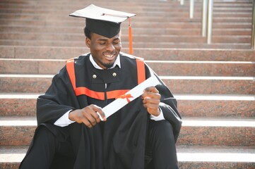 I have finally graduated. Happy young African man in graduation gowns holding diploma