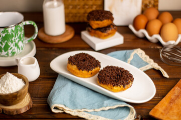 Donat Kampung or Donut Chocolate Sprinkles concept of chocolate doughnuts served on white plate,...