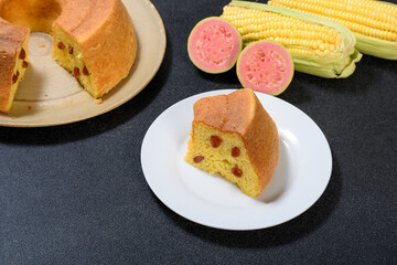  slice of corn cake with guava on a white prata, corn cob and guava fruit