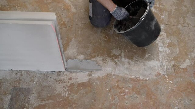 Experienced construction worker carefully applying concrete patching compound, meticulously filling and repairing visible crack on concrete floor surface