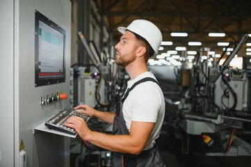 Factory male bearded worker is programming a CNC milling machine with copy space