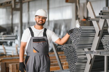 Smiling and happy indian employee. Industrial worker indoors in factory. Young technician with...