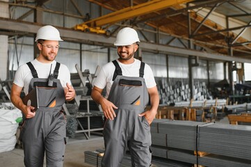 Metal processing, production of metal pipes and profiles. Two international workers at the factory.