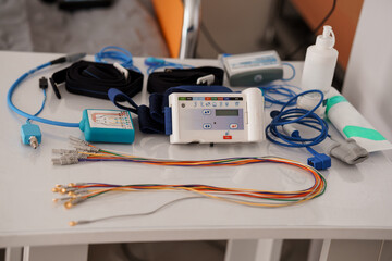 Polysomnography Setup for Sleep Study: ECG Monitor, Cables, Electrodes, White Table, Healthcare Diagnostic Equipment, Clinical Scene