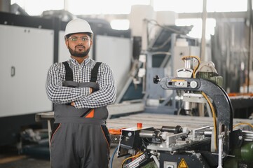 Operator of machine. Industrial worker indoors in factory. Young technician in white hard hat