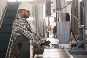 Young Indian male engineer wearing safety workwear standing in the factory