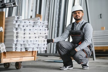 Smiling and happy indian employee. Industrial worker indoors in factory. Young technician with...