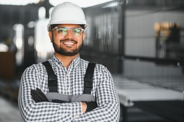 Operator of machine. Industrial worker indoors in factory. Young technician in white hard hat