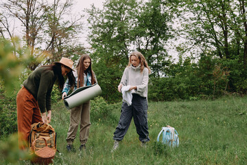 Active middle age woman preparing for outdoor fitness activity with friends in green forest,...