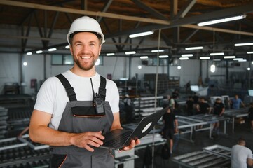 A young male engineer inspects the production of plastic window frames