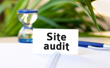 Site audit seo business concept text on a white notebook and hourglass, blue pen, green flowers
