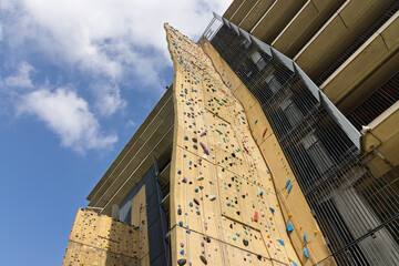 A massive outdoor climbing wall, studded with colorful holds, stretches skyward beside a modern building, offering an impressive challenge at Utrecht Science Park.