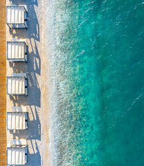 In the touristic holiday resort of Bodrum, there is a crystal clear, turquoise sea and private beach pavilions (bungalows and cabanas) lined up on a luxurious beach. Aerial photo