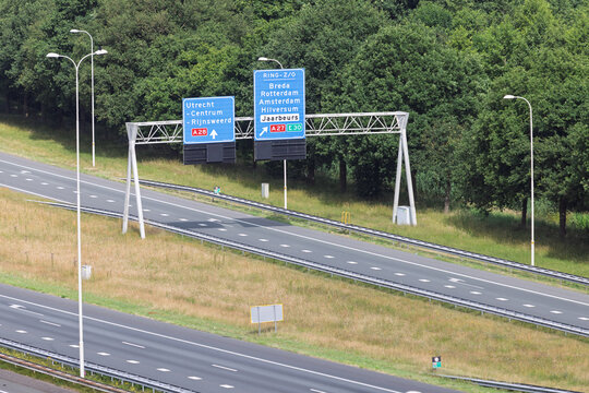 Dutch highway signage near Utrecht directs traffic for major cities and the Jaarbeurs exhibition center, set against a backdrop of green trees