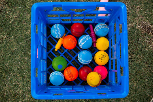 colourful kids cricket balls and bails in a blue milk crate