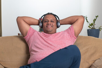 A man wearing headphones is sitting on a couch