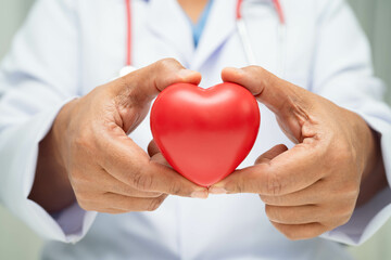 Asian woman doctor holding red heart for health in hospital.
