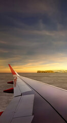 Airplane wing speeding on runway at takeoff with a landscape view of a sunset scene. Summer...