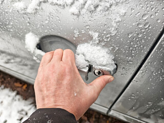 Snow-covered car handle during a cold snap with accumulation of snow and ice droplets in a winter...