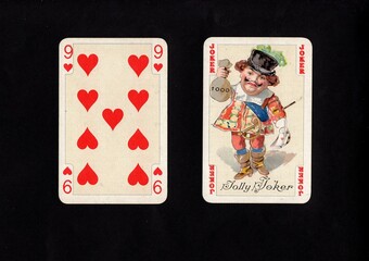A pair of vintage playing cards featuring a joker isolated on a black background.