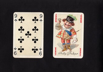 A pair of vintage playing cards featuring a joker isolated on a black background.