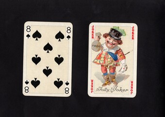 A pair of vintage playing cards featuring a joker isolated on a black background.