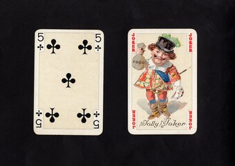 A pair of vintage playing cards featuring a joker isolated on a black background.